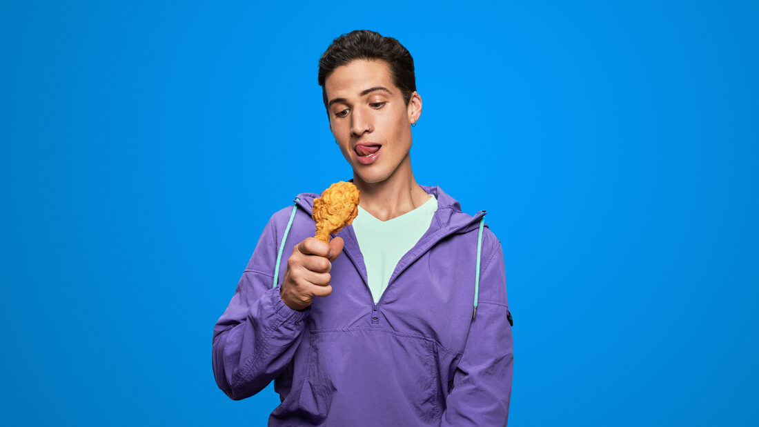 Hombre disfrutando pollo frito sobre fondo azul