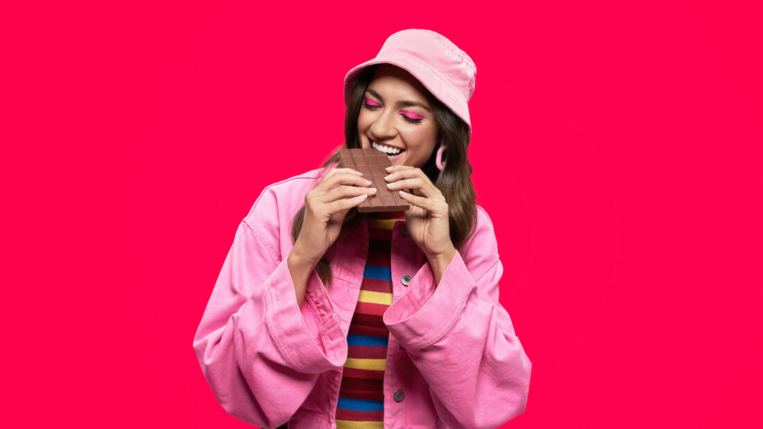 Mujer disfrutando chocolate sobre fondo rosa