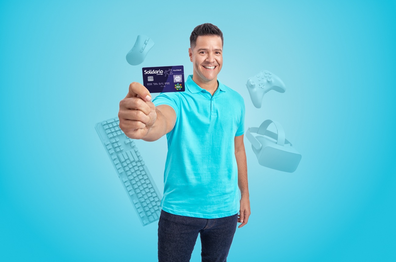 Hombre mostrando la tarjeta Banco Solidario Platinum entre dispositivos tecnológicos